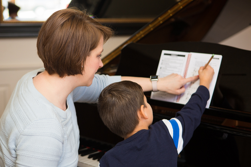 Woman teaching a young boy piano