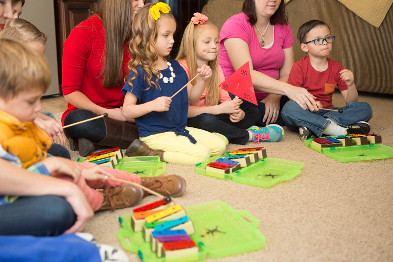 A group of young kids learning to play instruments on the floor.