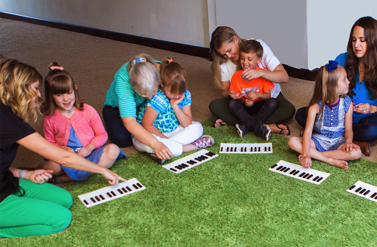 A group of happy kids sitting on the floor learning piano basics.